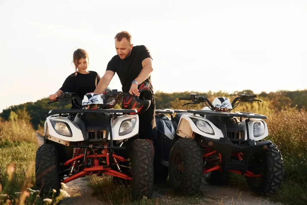 Showing how the machine works. Father and daughter are with ATV outdoors.
