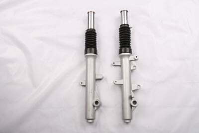A pair of Front Suspension (JZB-AT003) mounted on a white surface using a holder.