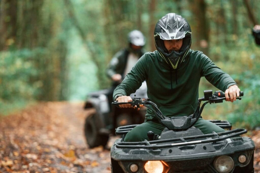 ATV riders on a dirt track in the woods