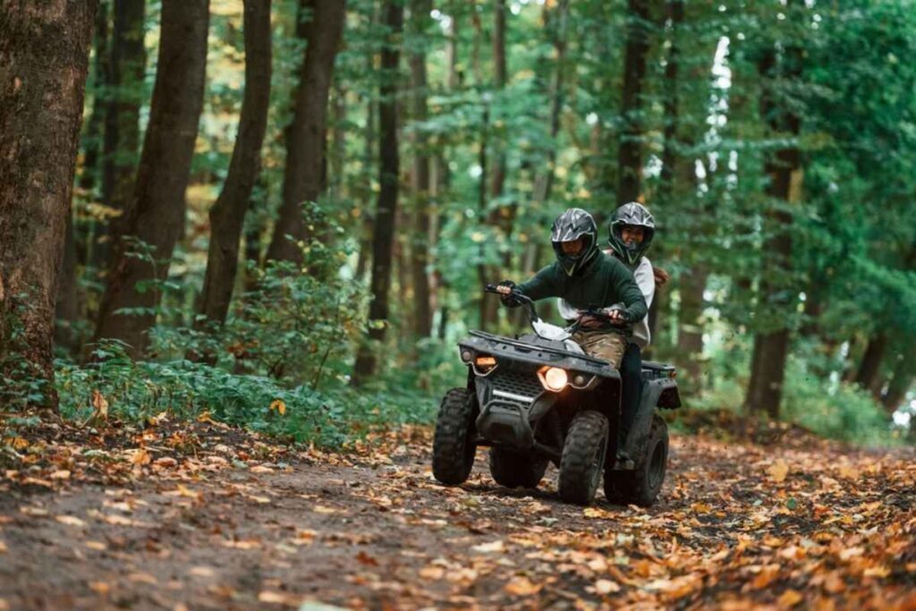 Couple driving an ATV in the woods