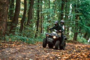 Couple driving an ATV in the woods