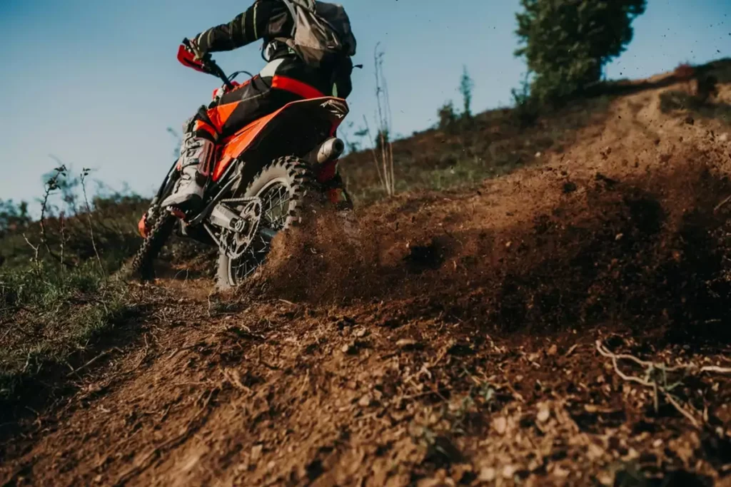 Professional enduro bike rider on action, dirt ride on the muddy road.